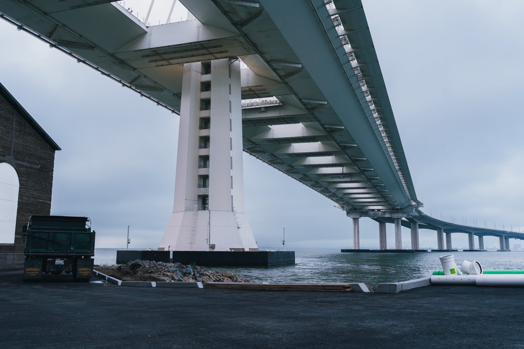 The base of a bridge tower with a work truck parked beside it