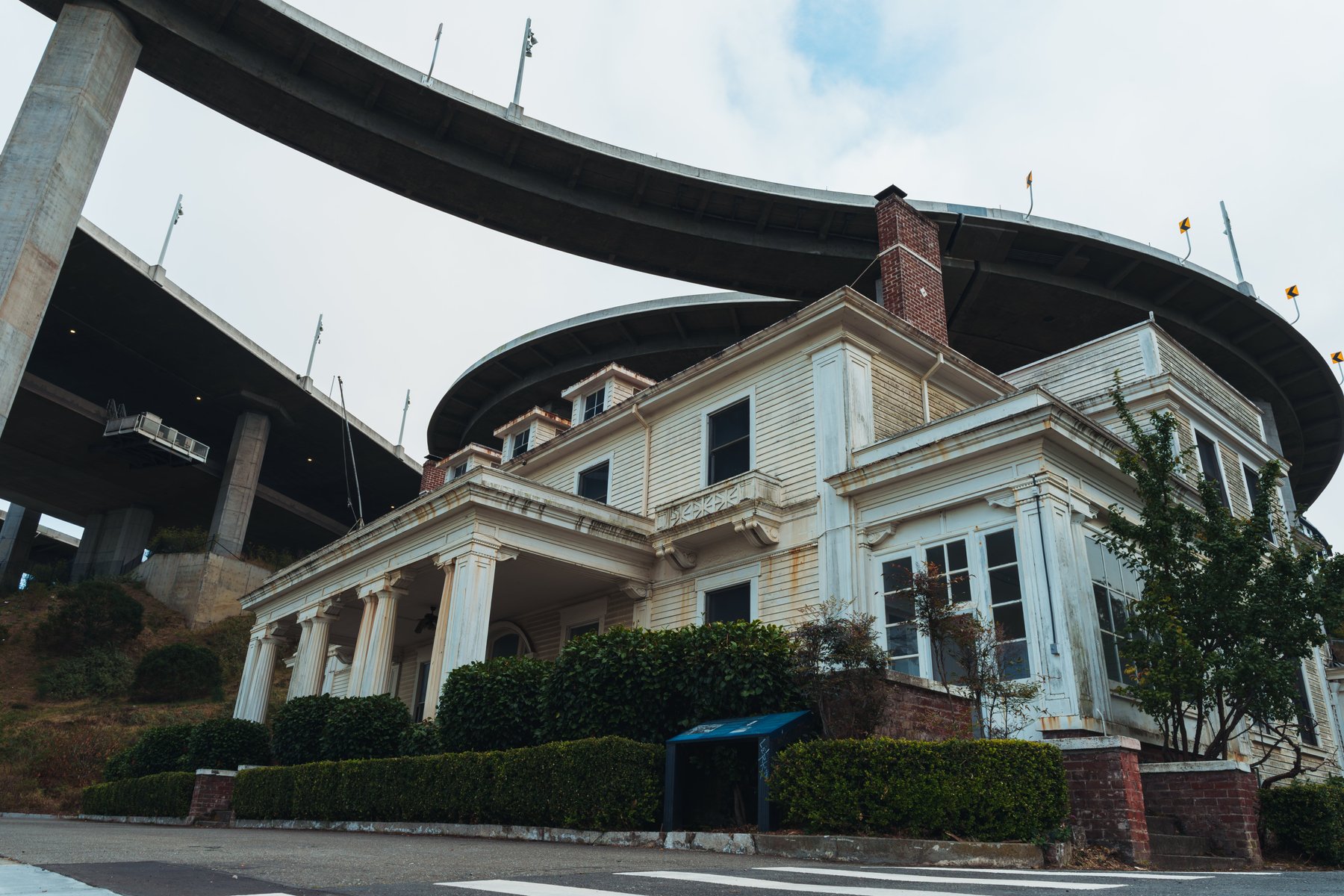 A historic Victorian building beneath a freeway overpass, seen in daylight