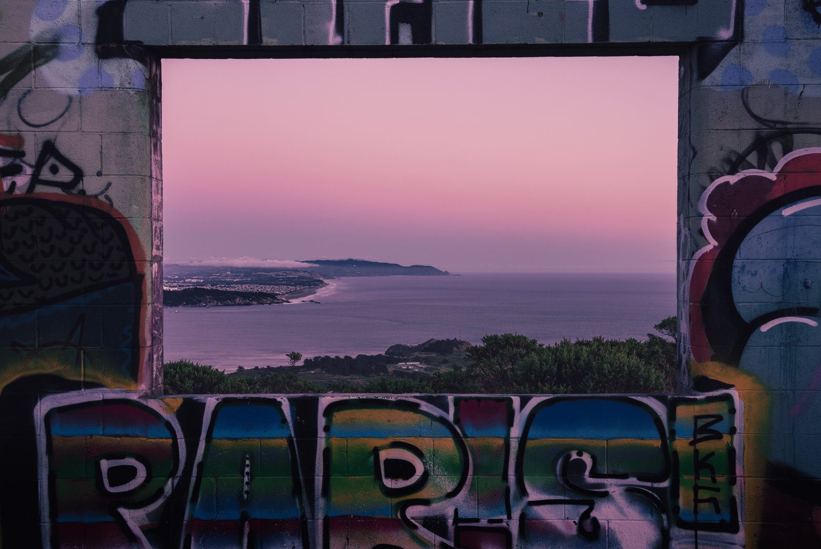 The Marin coastline at dusk framed through a graffiti bunker window