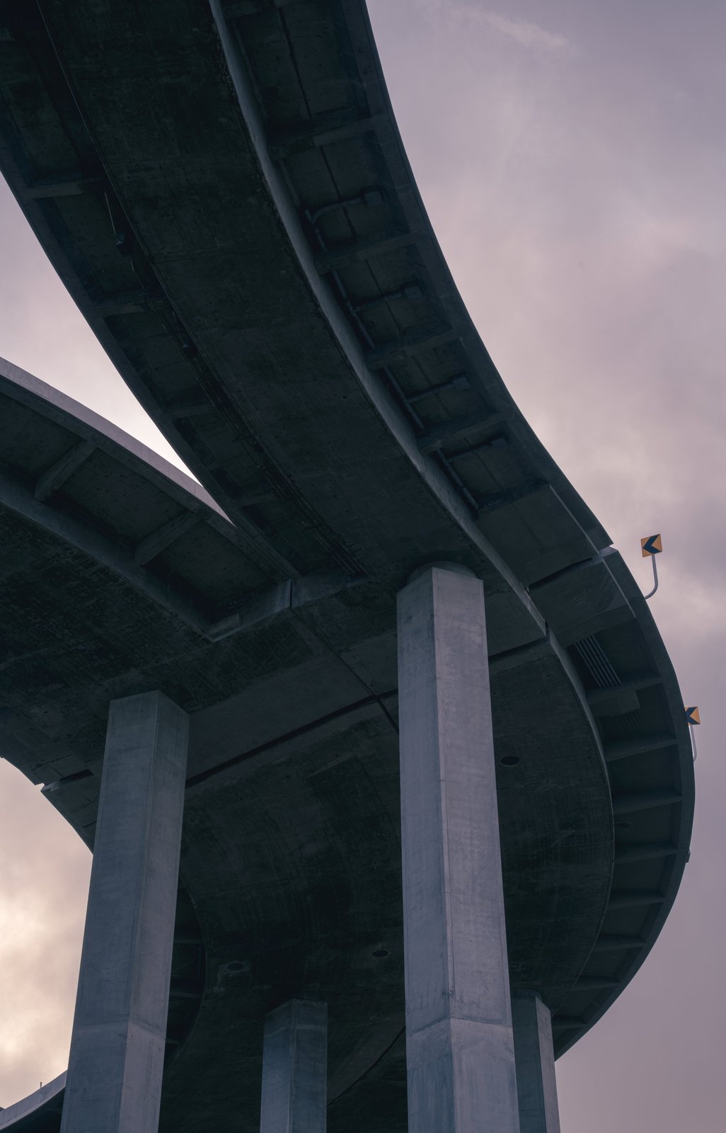 Looking straight up at the underside of a curving freeway overpass