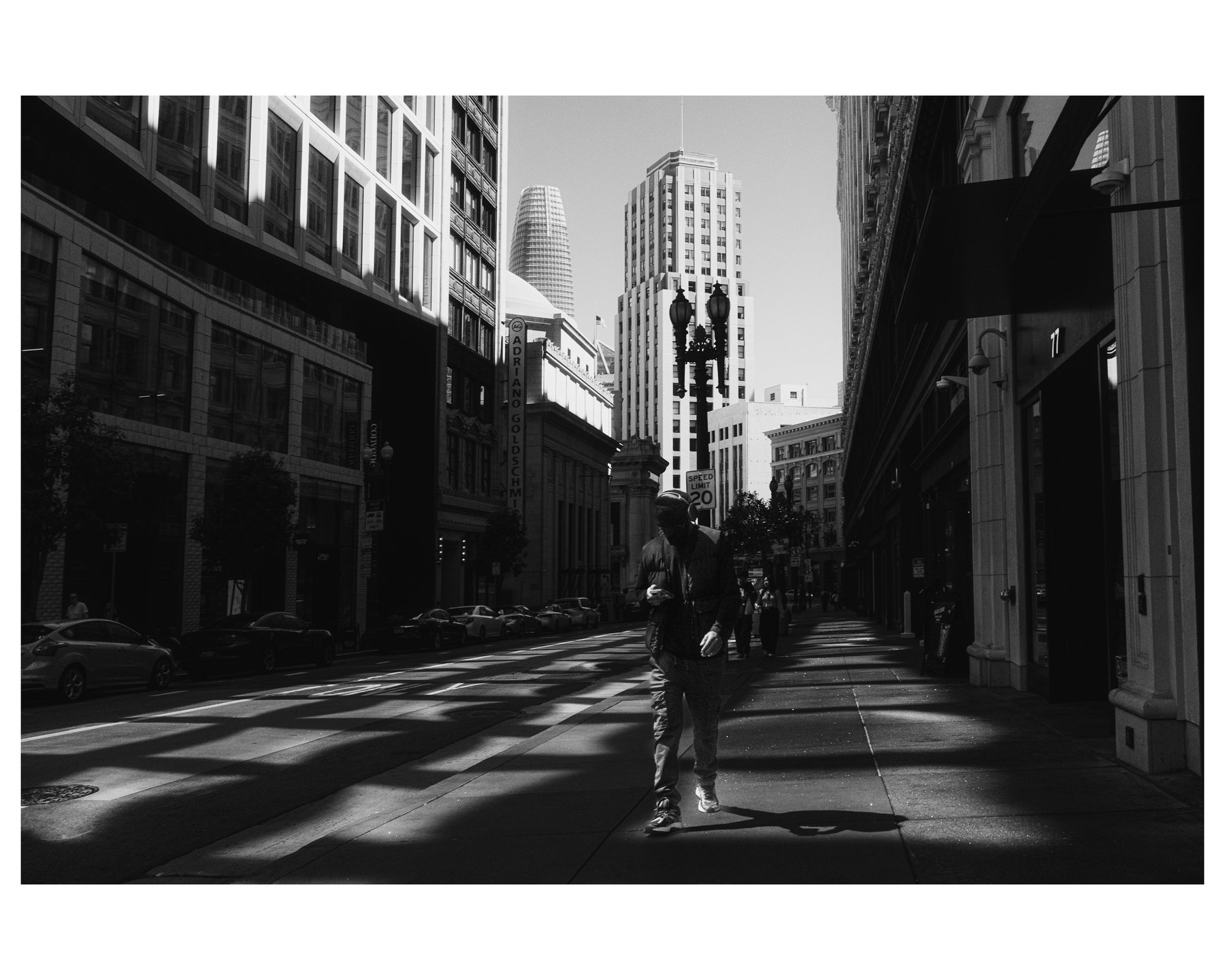 A lone figure walking through dappled shadow with the Salesforce Tower in the background