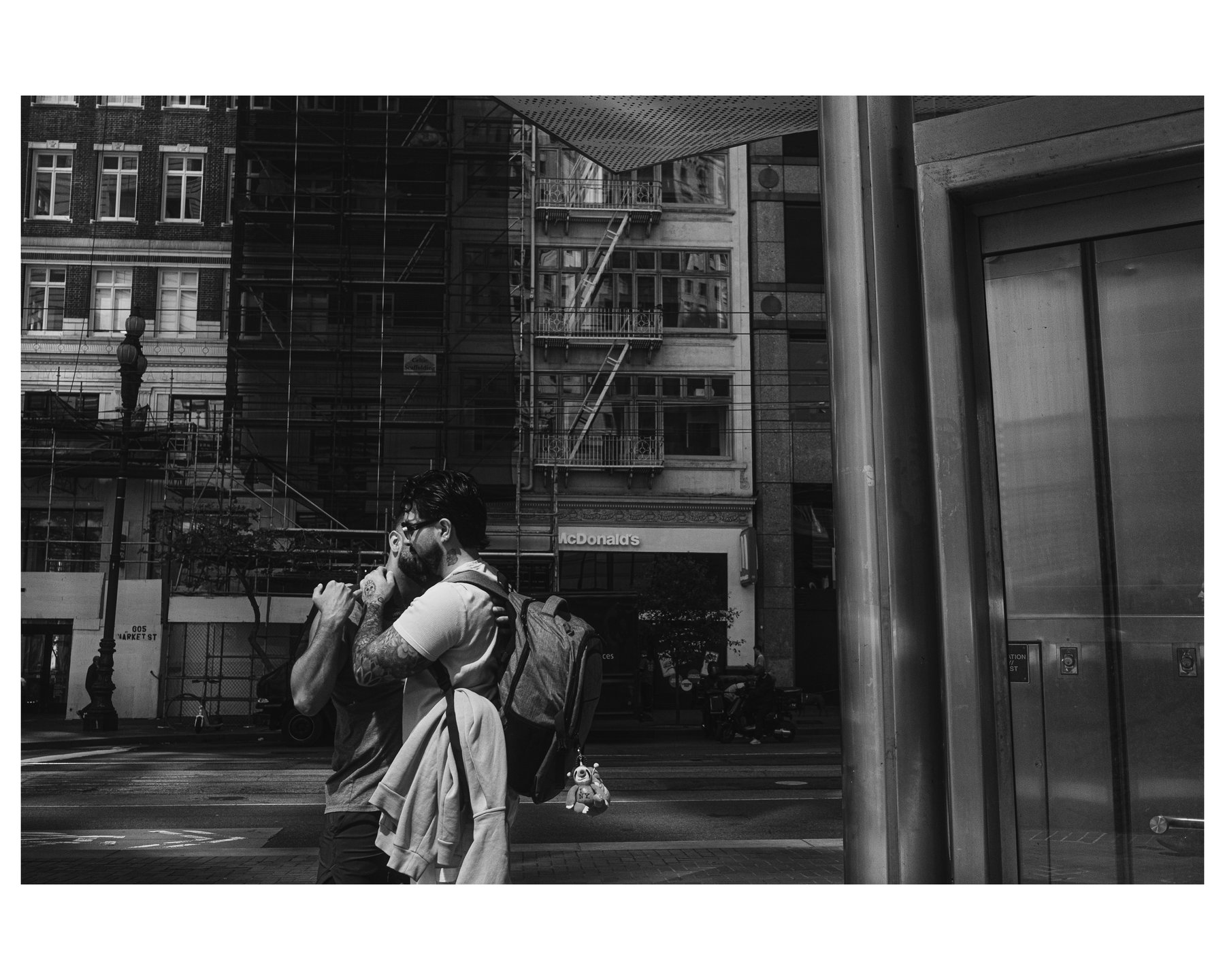 Two men embracing on a street corner near a McDonald's storefront