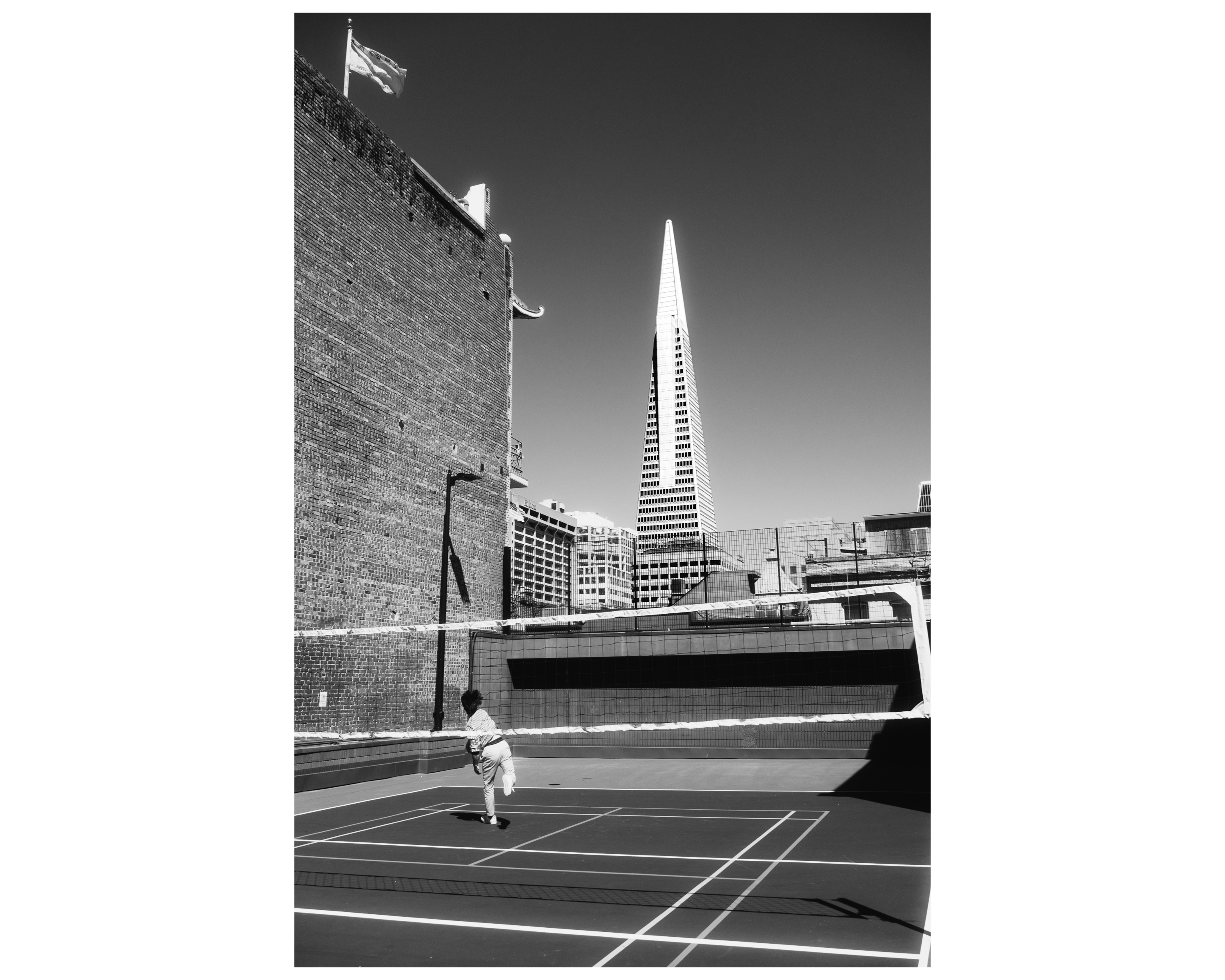 A lone figure on a rooftop badminton court with the Transamerica Pyramid behind