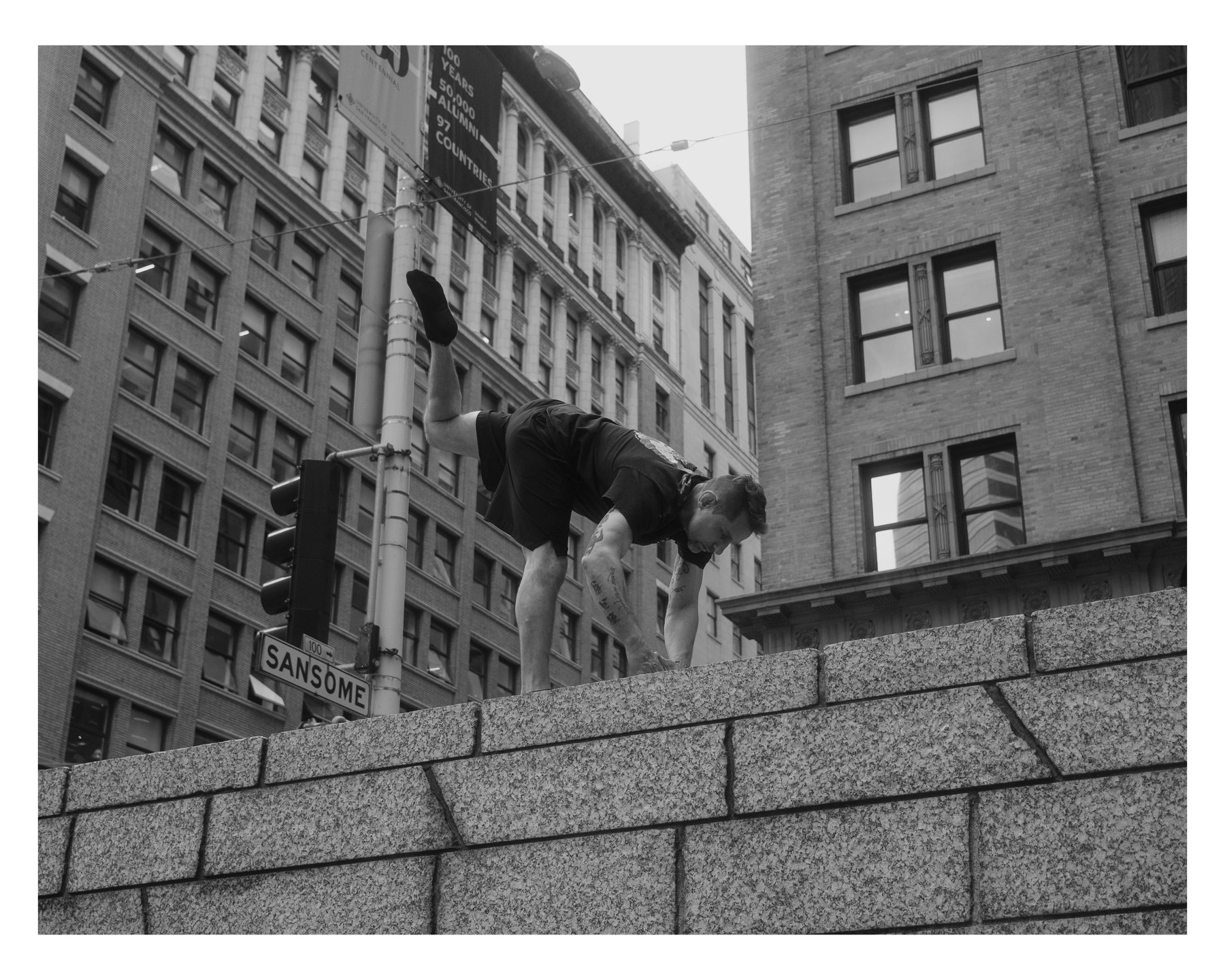 The same man now in a handstand-like pose on the granite wall