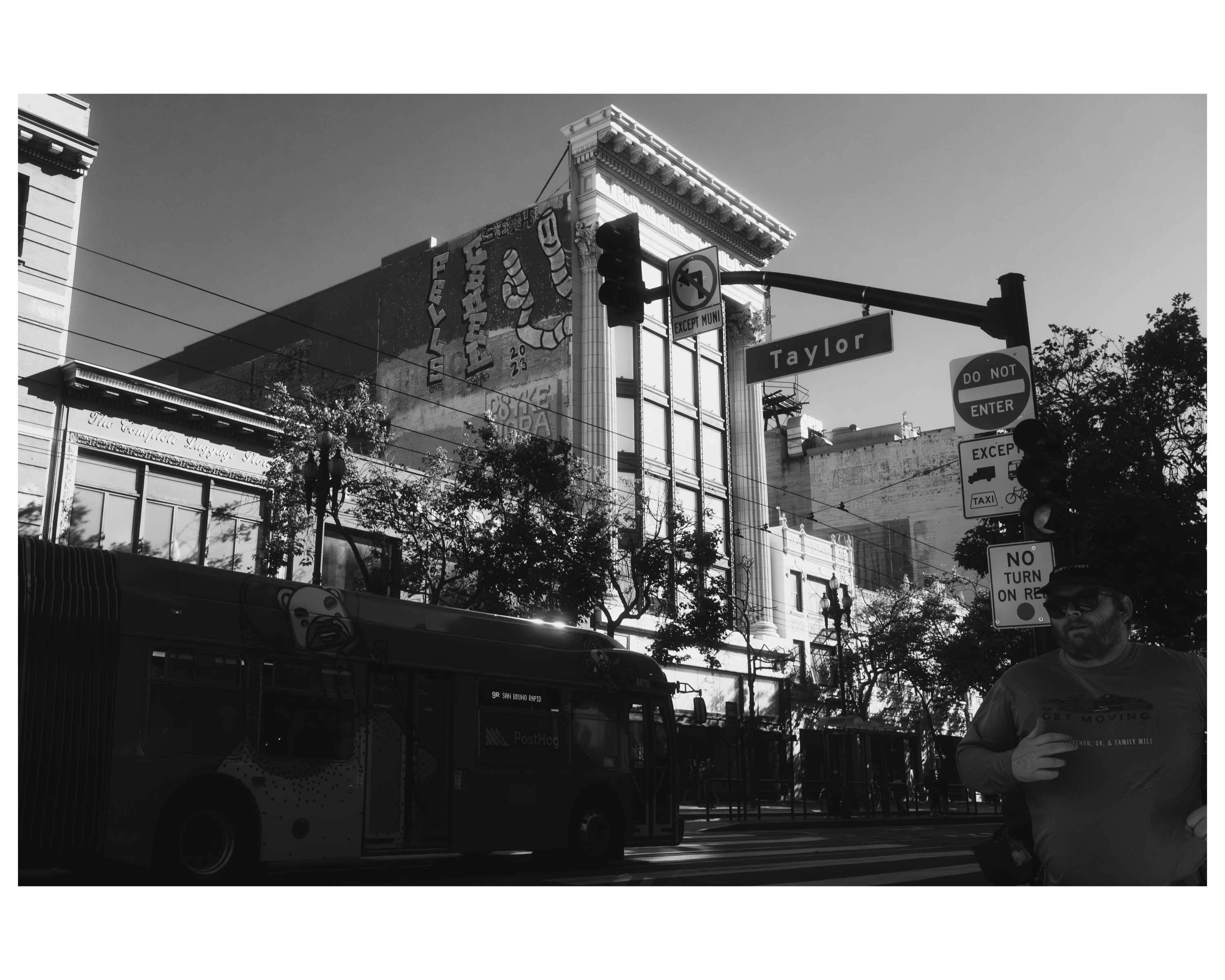 A Muni bus passing a mural-covered building at Taylor Street